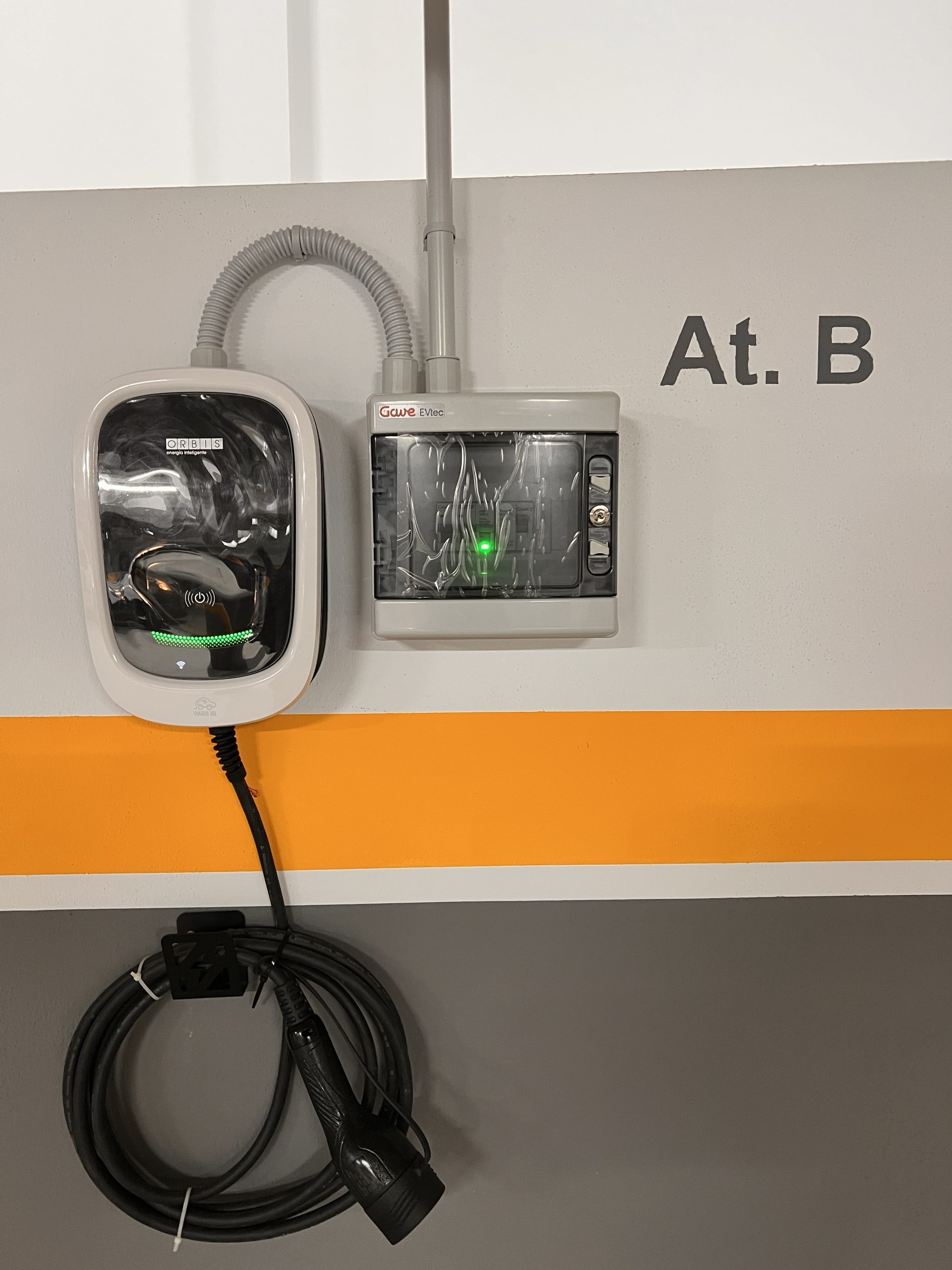 Cargador de coche eléctrico con cable enrollado en la plaza de garaje.