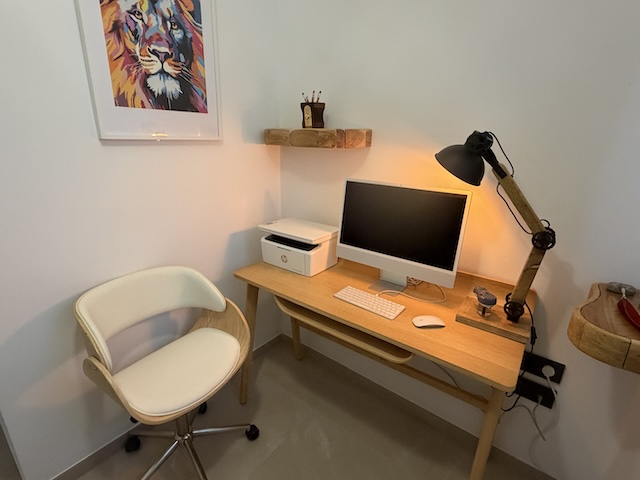 Oficina del ático en Vejer con silla de madera tapizada, escritorio y cuadro decorativo de león.