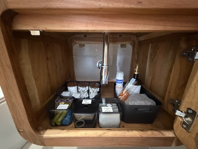 Amenities de baño organizados en el interior del mueble del lavabo, con productos de higiene y básicos.