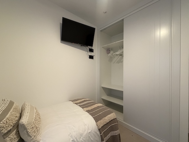 Interior de armario empotrado con estantes y espacio para colgar ropa en dormitorio.