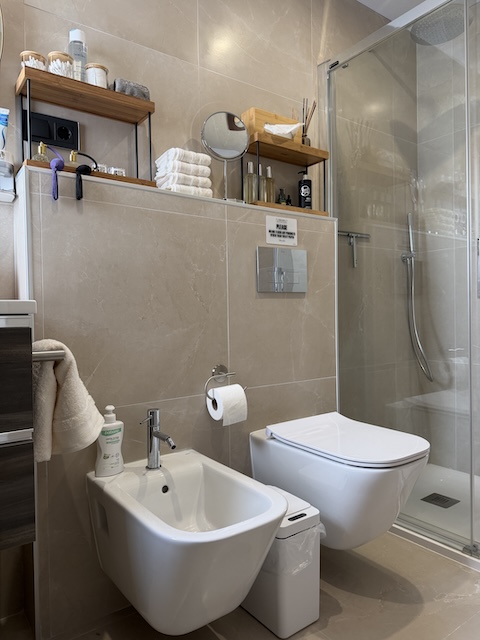 Bidé y WC junto a ducha con mampara de cristal en baño principal.