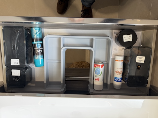 Cajón del lavabo organizado con productos de aseo, artículos dentales y accesorios de afeitado.