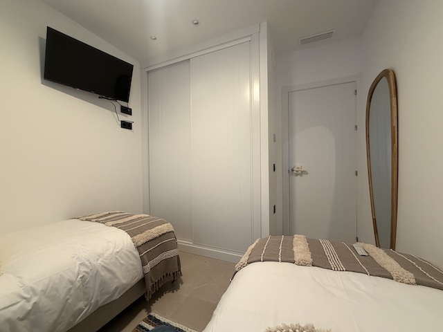 Armario empotrado blanco con puertas correderas en dormitorio, junto a la zona de descanso.