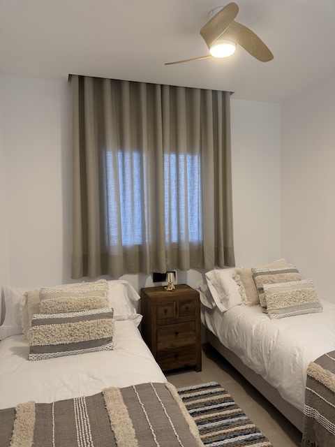 Vista frontal del dormitorio con dos camas individuales y mesita de noche en el centro.