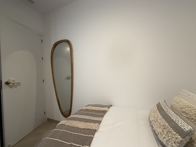 Espejo de cuerpo entero con marco de madera junto a la cama en dormitorio.