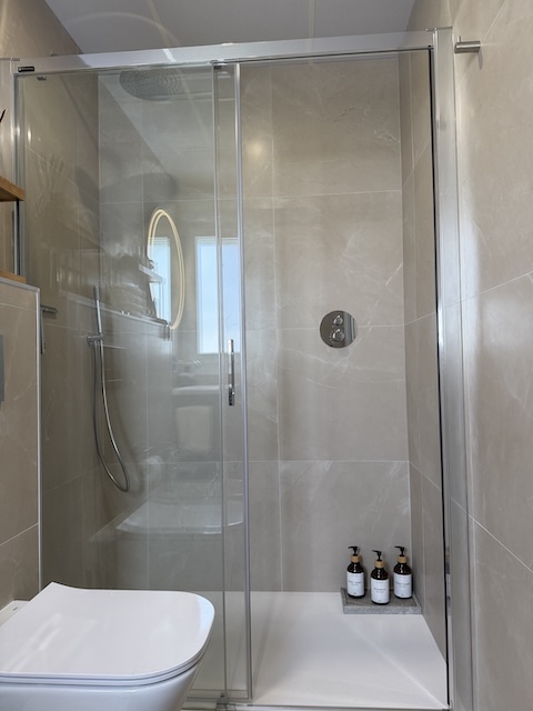 Ducha a ras de suelo con mampara de cristal y rociador superior efecto lluvia.