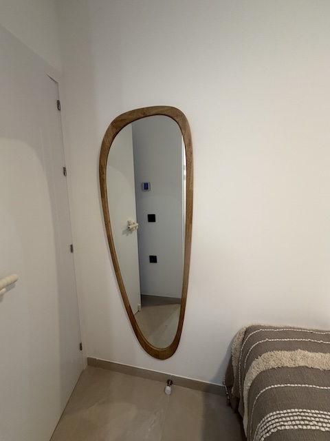 Espejo de cuerpo entero con marco de madera en pared del dormitorio.