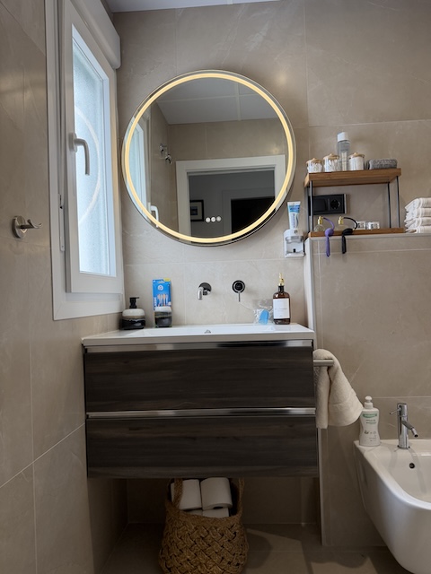 Mueble de lavabo con espejo retroiluminado y zona de almacenaje en baño principal.