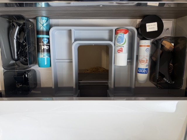 Máquina de afeitar con accesorios y organizadores dentro del cajón del mueble del lavabo.