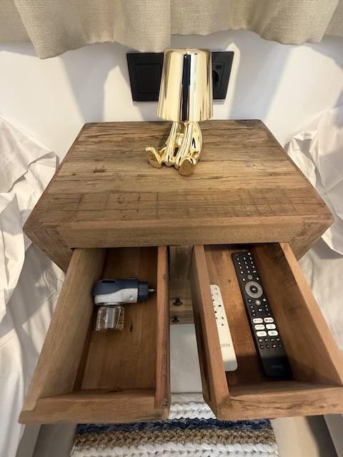 Mesita de madera con cajones abiertos, lámpara y accesorios organizados.