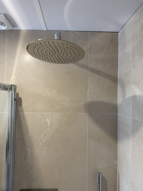 Rociador superior de ducha efecto lluvia en baño principal.