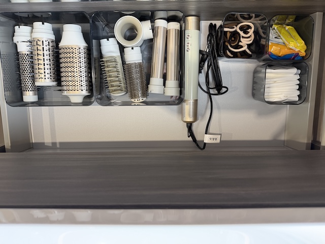 Secador de pelo con accesorios y cepillos guardados en el cajón del baño principal.