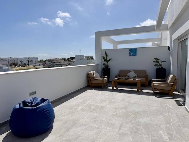 Terraza privada con puff azul y zona de estar en ático vacacional en Vejer