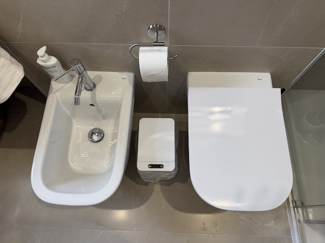 Vista superior de bidé, WC y papelera en baño principal.